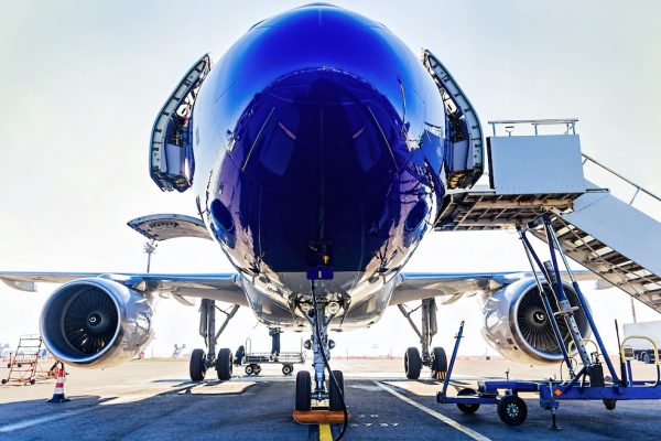 Fueling and final checking aircraft before taking off, view of open doors, turbines and boarding stairs, plane landing gear