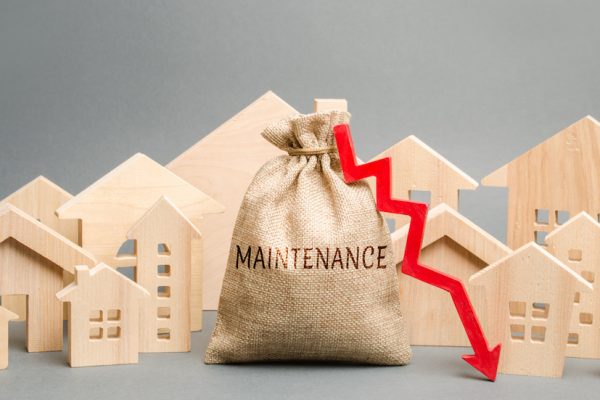 A bag with the word Maintenance, wooden houses and down arrow. Reducing the cost of maintaining the house. Improving energy efficiency and environmental friendliness of buildings, reducing energy cost