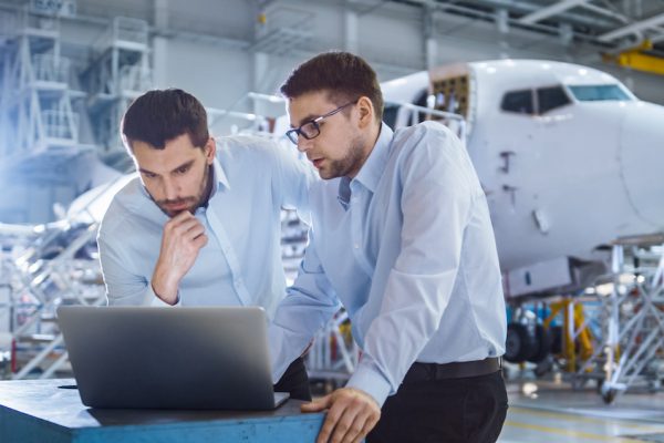 Two Aircraft Mechanics Working and Having Conversation next to Laptop Computer